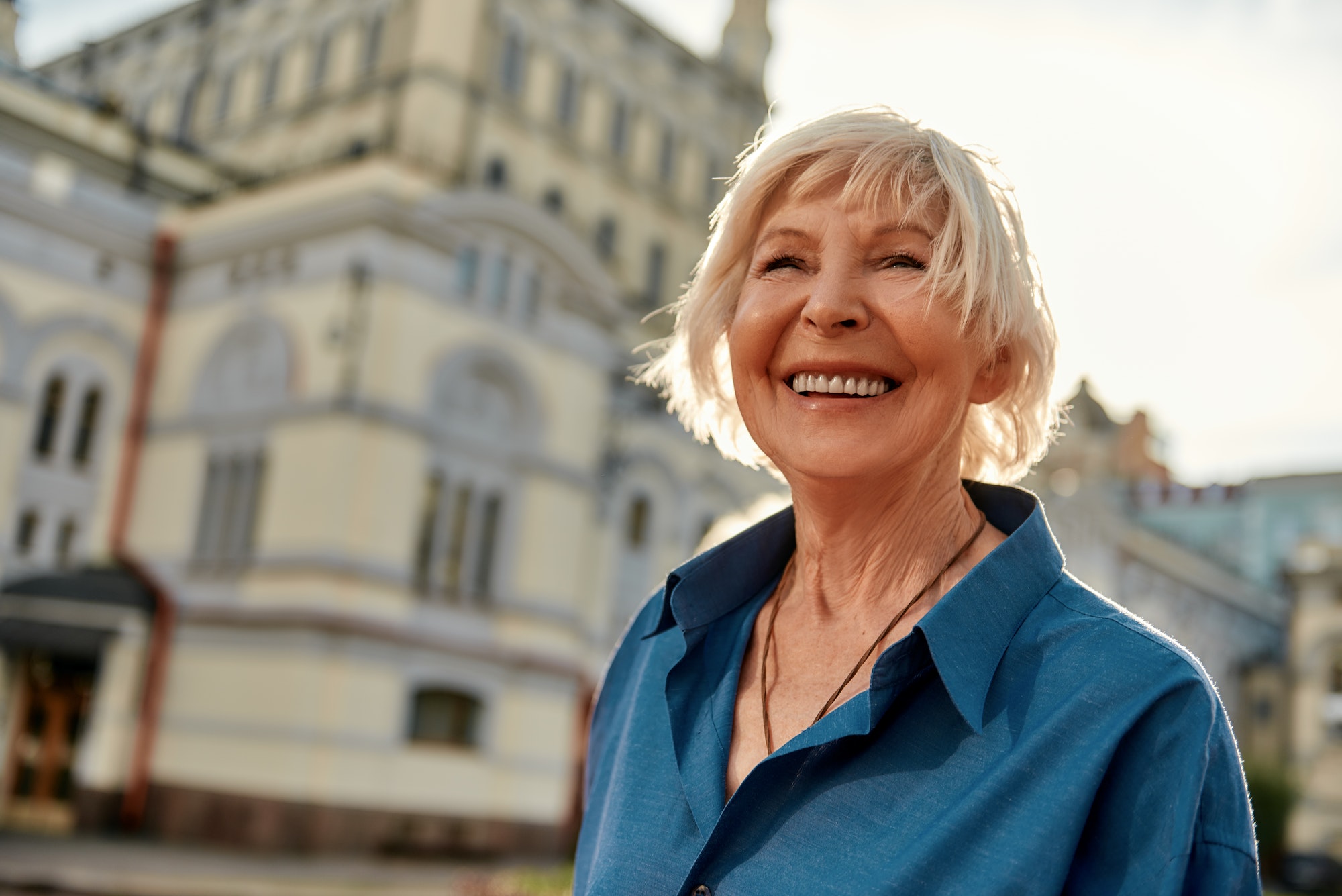 Good mood! Portrait of beautiful and happy senior woman smiling while standing outdoors on a sunny