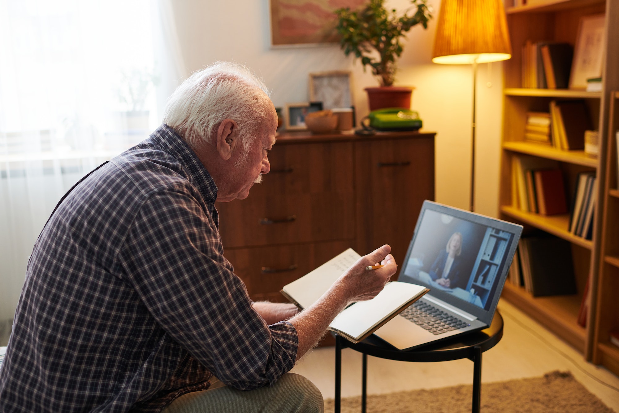 Old man having online consultation on laptop